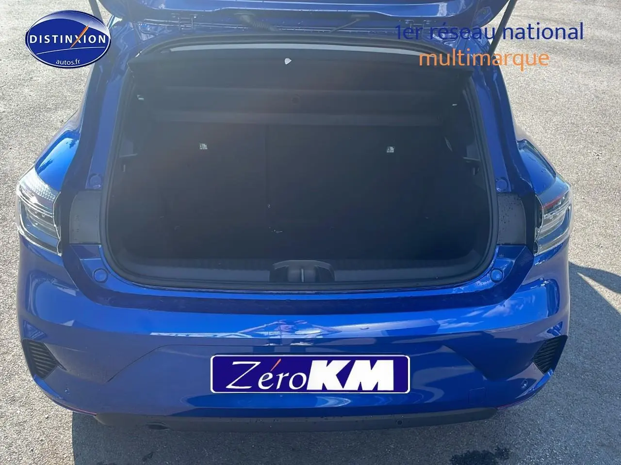 Vue arrière d'une Renault Clio V bleu iron avec coffre ouvert montrant l'espace de chargement vide.