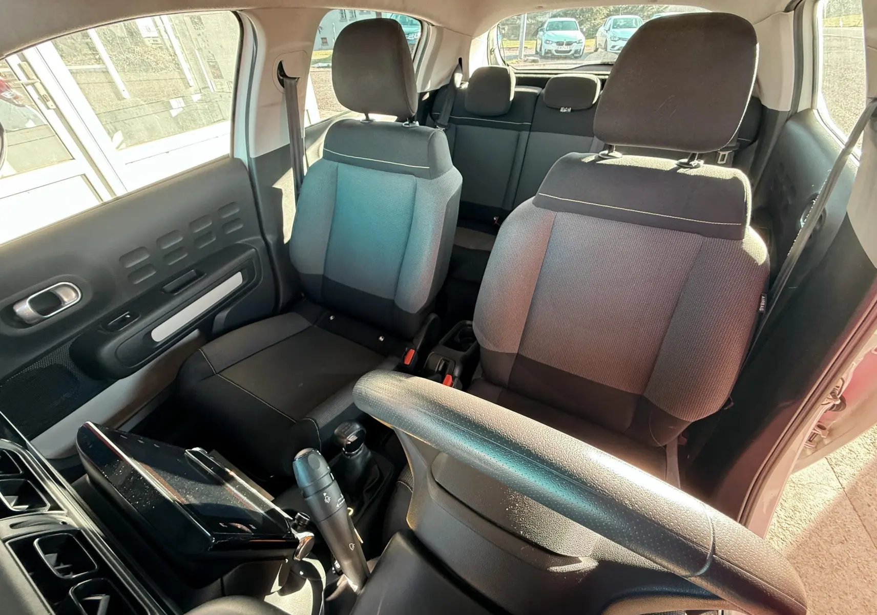 Vue intérieure côté conducteur de la Citroën C3 2017, sièges tissu gris noir et volant noir visible.