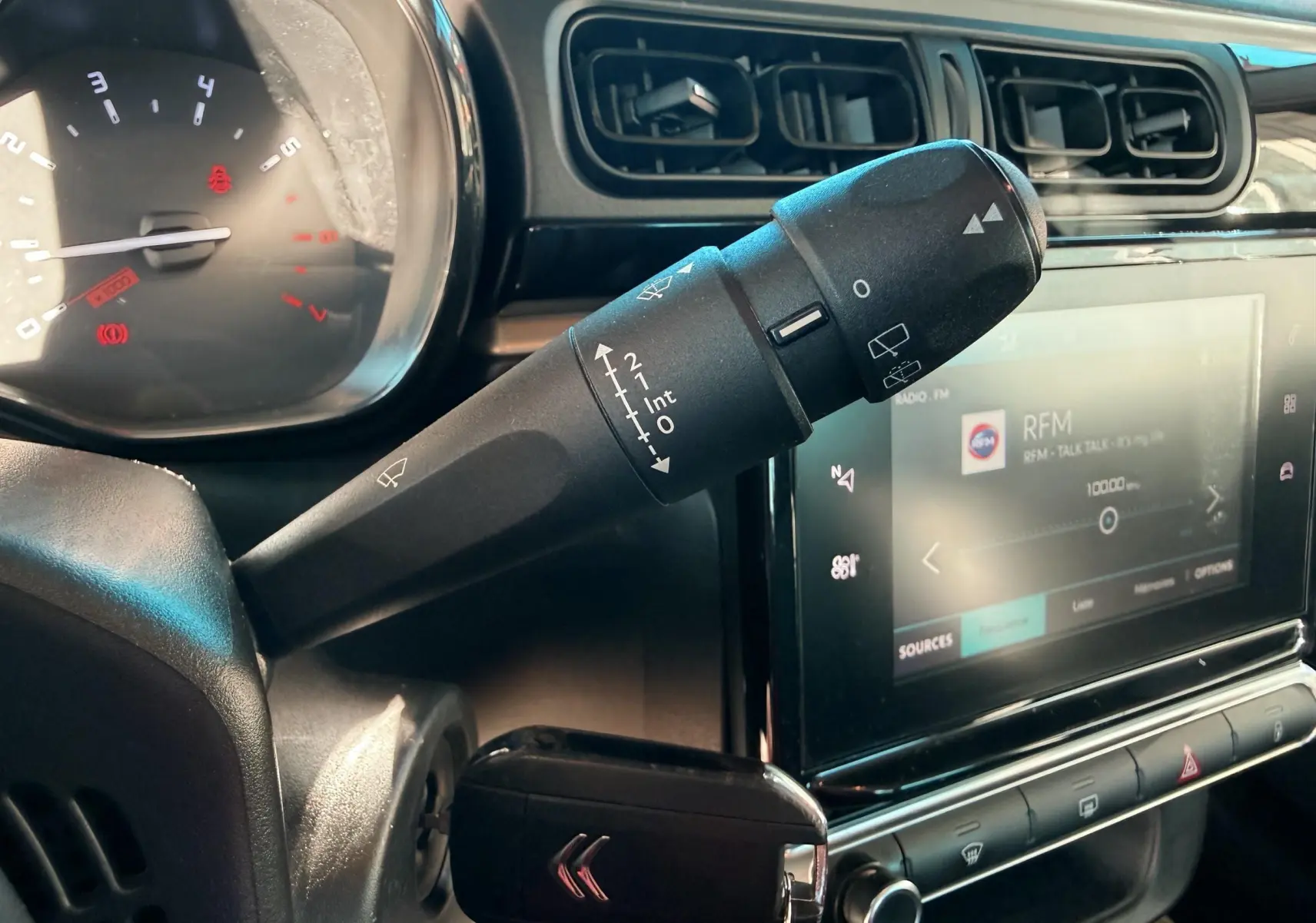 Gros plan sur la commande d’essuie-glace et tableau de bord noir de la Citroën C3 2017, intérieur gris et écran tactile.