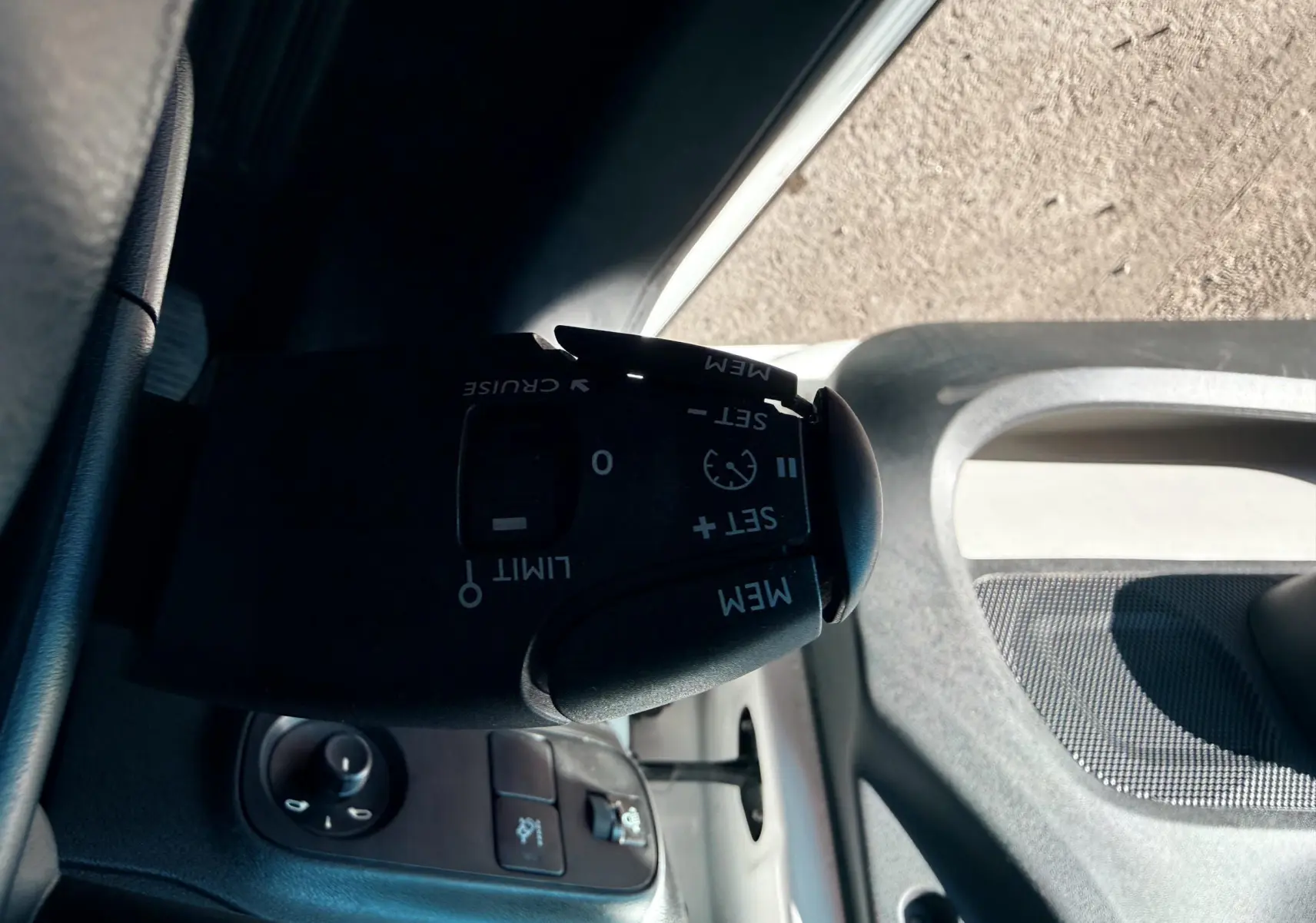 Gros plan sur la commande de régulateur de vitesse à gauche du volant d’une Citroën C3 blanche, intérieur gris-noir.