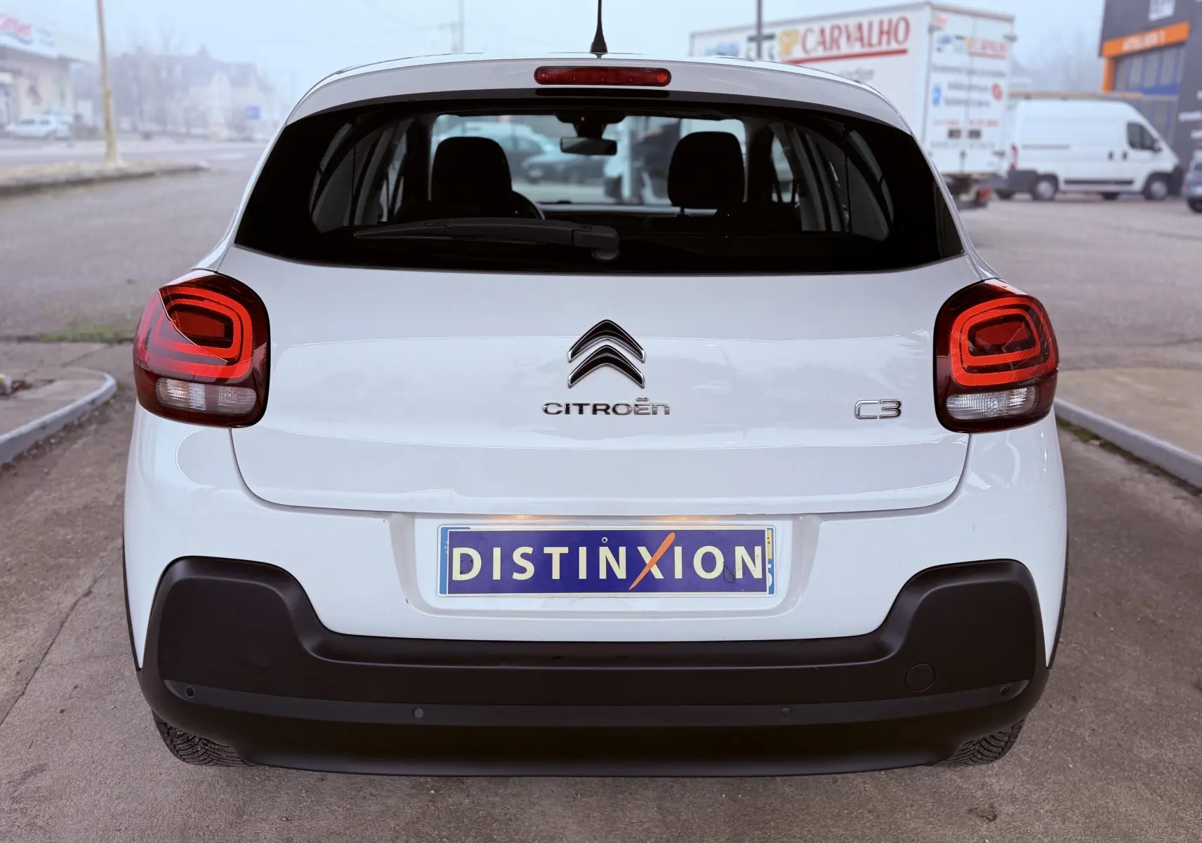 Vue arrière d'une Citroën C3 blanche de 2017 avec feux arrière rouges et plaque d'immatriculation Distinxion.