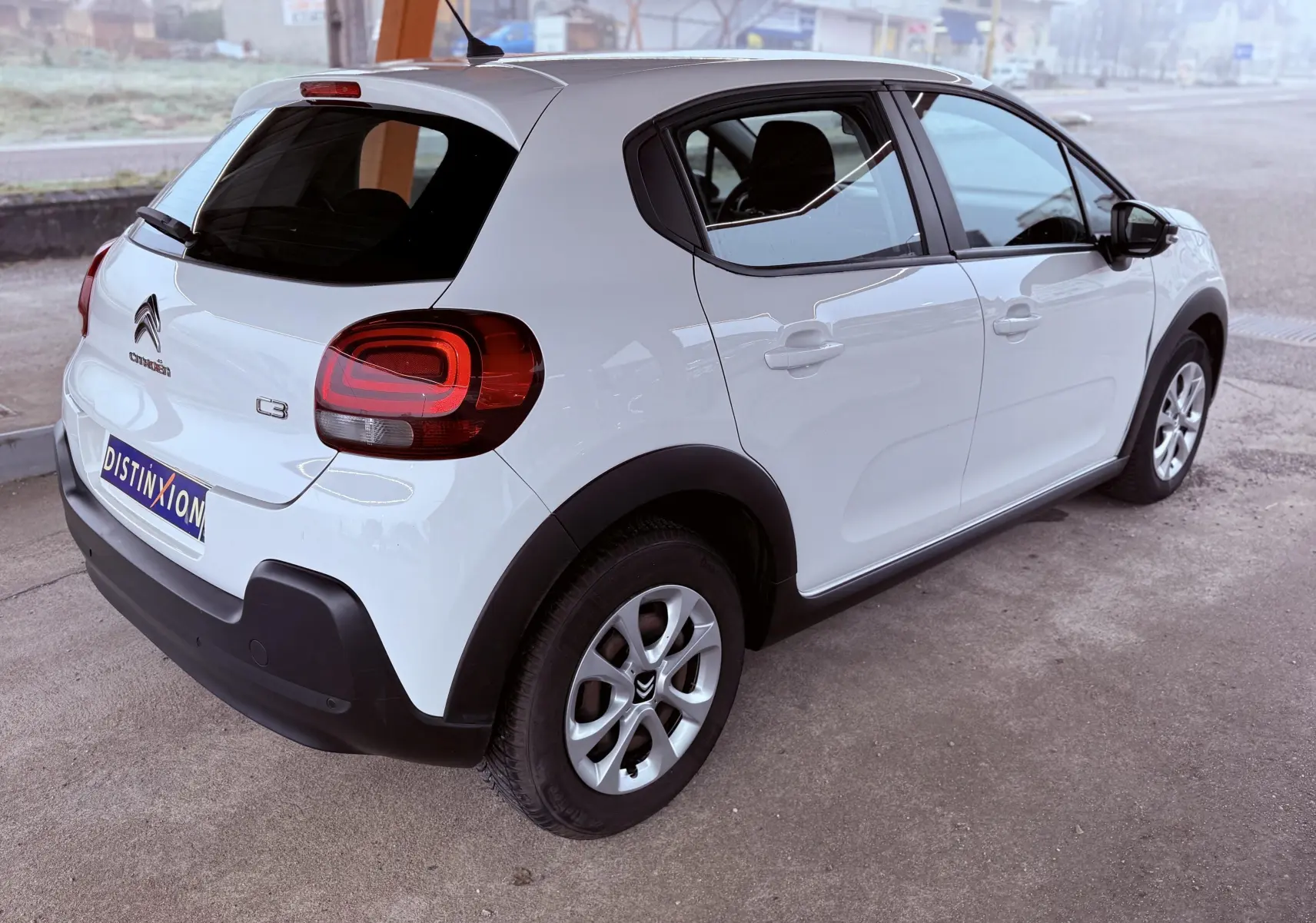 Vue 3/4 arrière droite d'une Citroën C3 blanche 5 portes avec feux arrière distinctifs et jantes alliage.