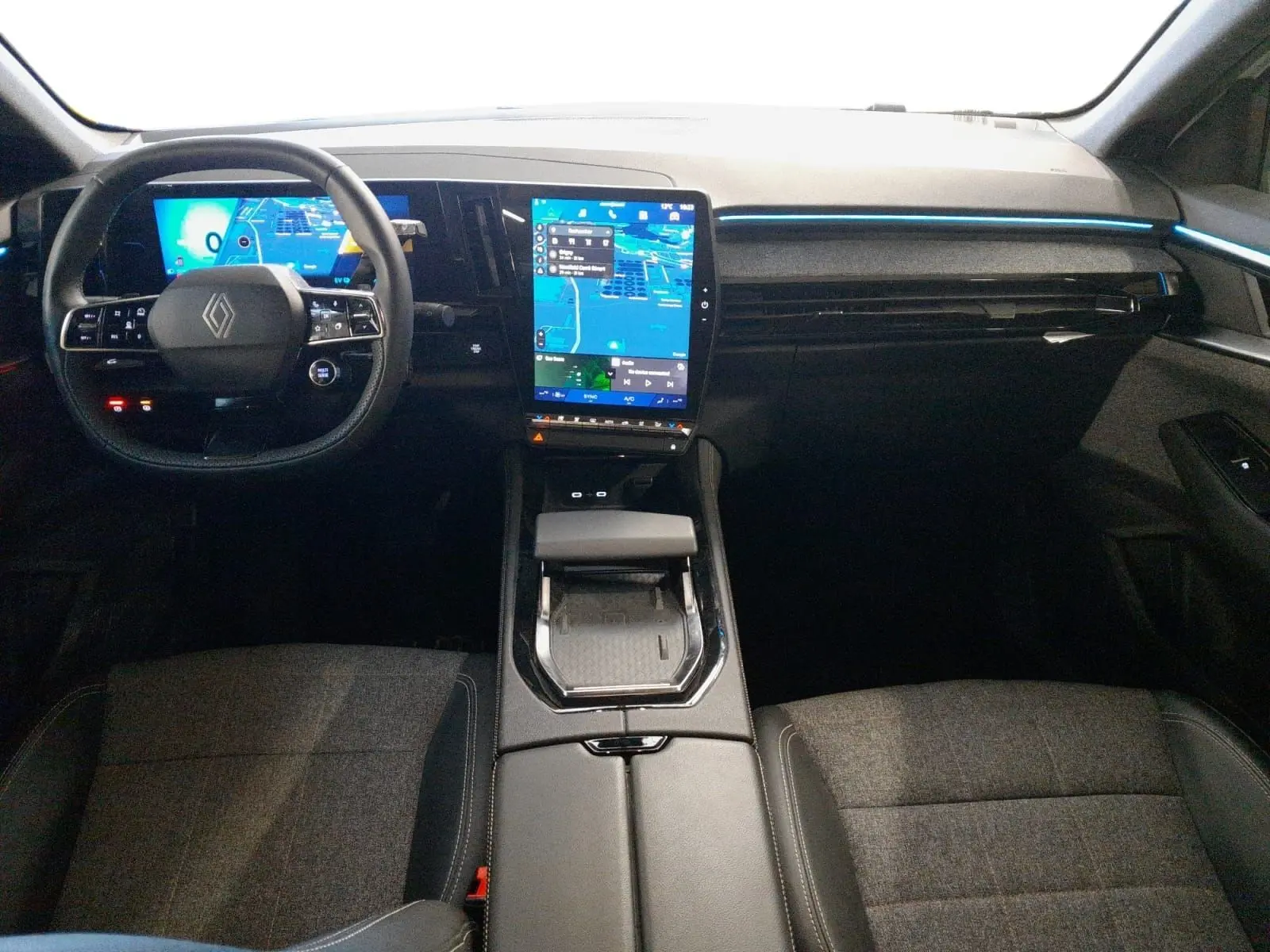 Vue intérieure avant du Renault Espace 2025 avec tableau de bord numérique, écran tactile vertical et ambiance lumineuse bleue.