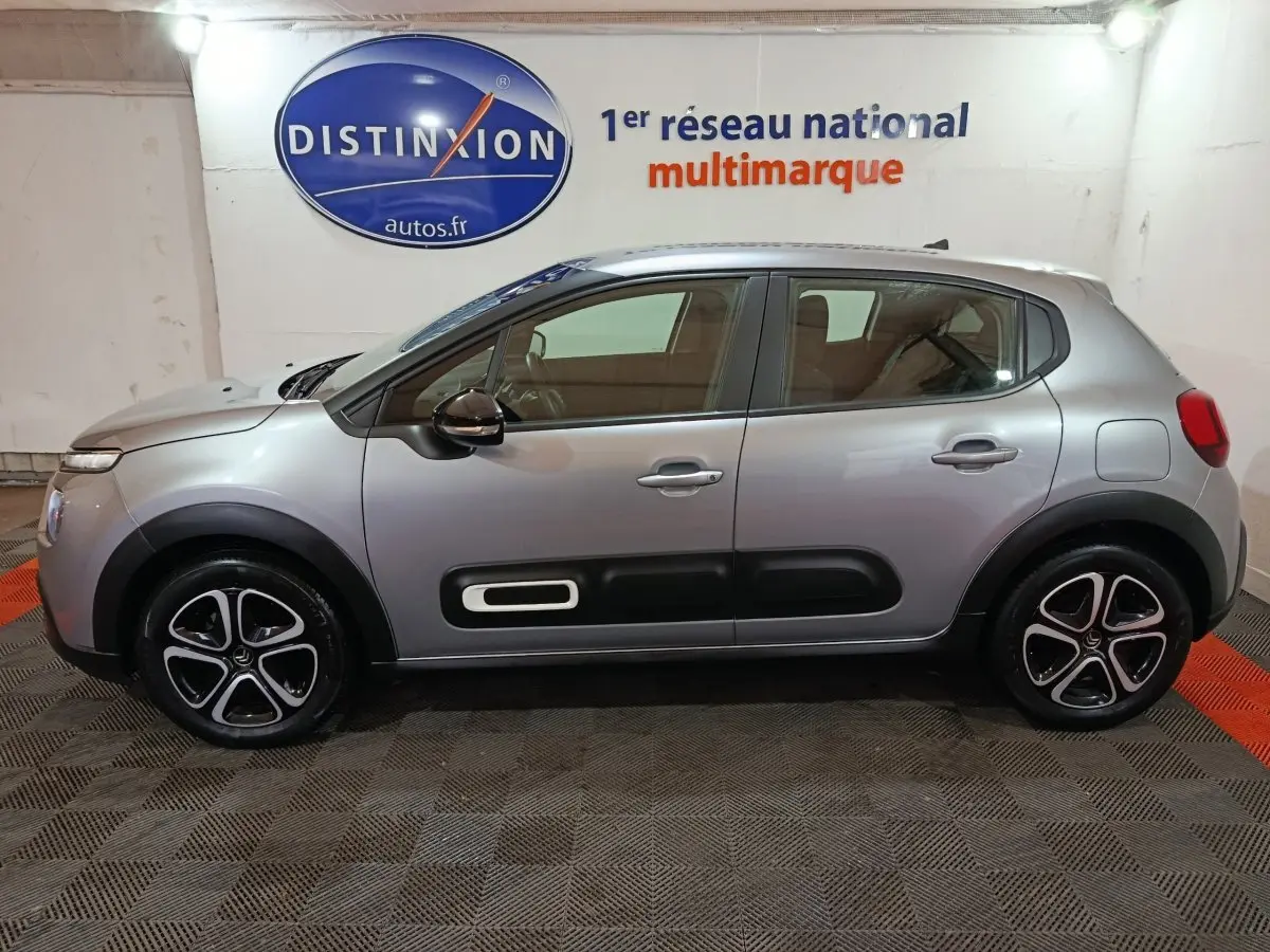 Vue de profil côté gauche d'une Citroën C3 gris clair 2024 avec protections latérales noires et jantes stylisées.