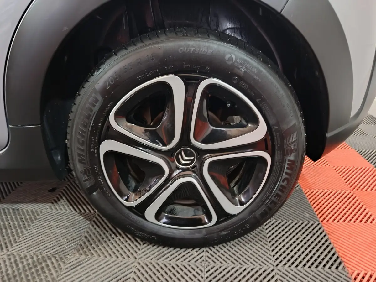 Gros plan sur la roue avant droite grise claire d'une Citroën C3 2024 avec jante alliage noire et argentée distinctive.