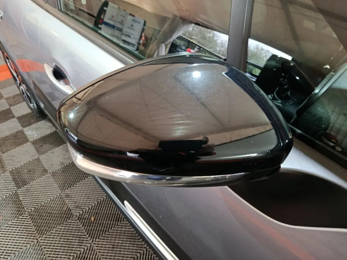 Rétroviseur droit noir brillant avec caméra sur Citroën C3 gris clair, vue rapprochée côté conducteur.