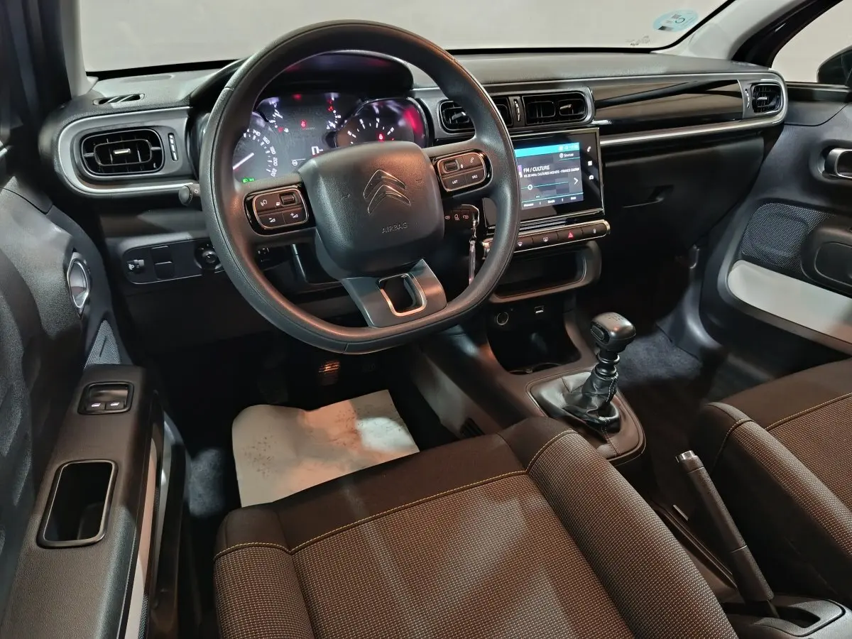 Intérieur avant de la Citroën C3 gris clair, vue côté conducteur, volant multifonctions et écran tactile central visible.