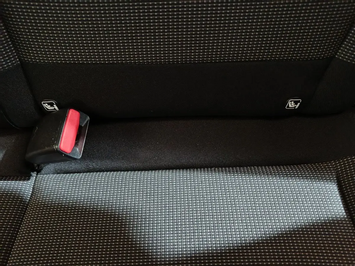 Gros plan sur la banquette arrière en tissu gris à motifs, avec boucle de ceinture de sécurité rouge visible.