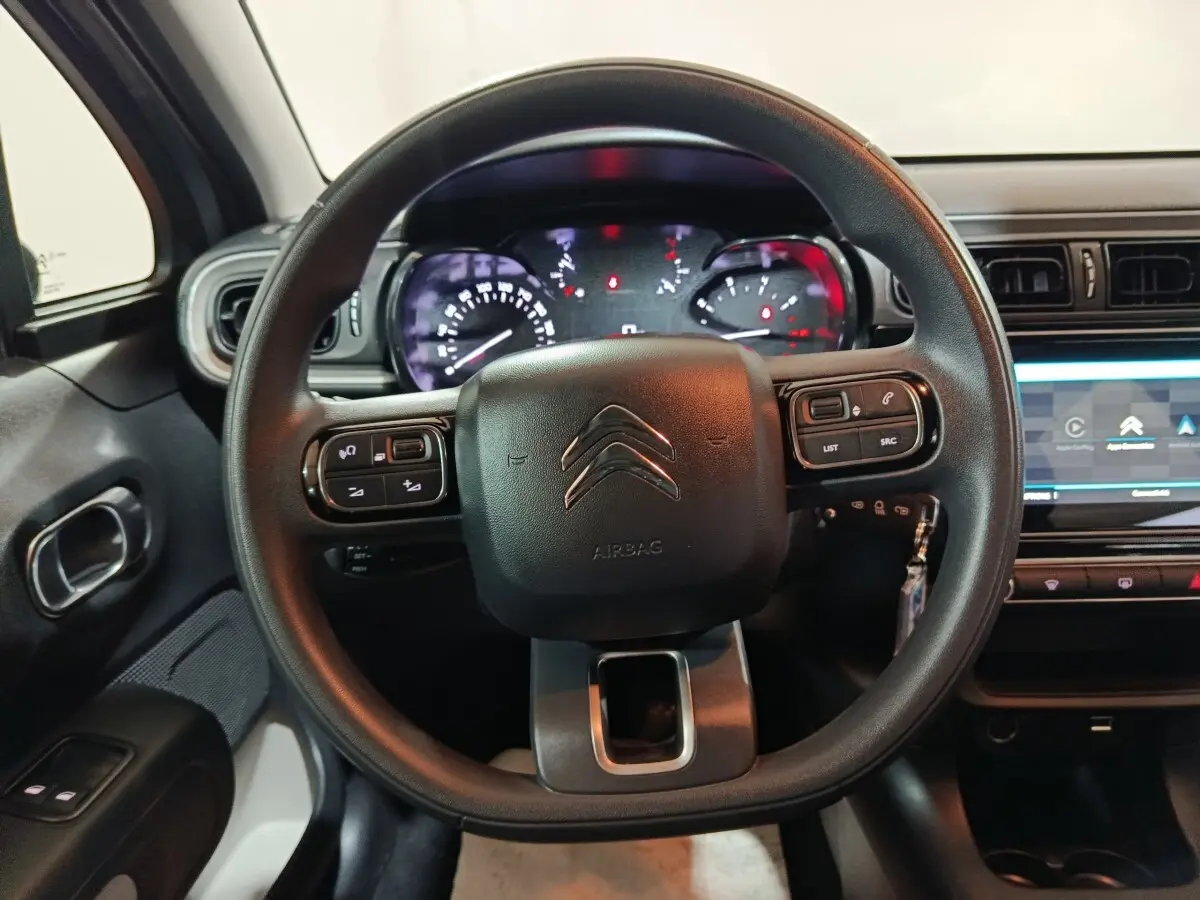 Vue rapprochée du volant multifonctions noir et du tableau de bord numérique de la Citroën C3 2024 gris clair.