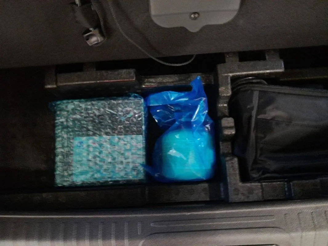 Rangement intérieur du coffre de la Peugeot 408 PHEV 180 e-EAT8 Allure noir, vue plongeante sur les accessoires rangés.