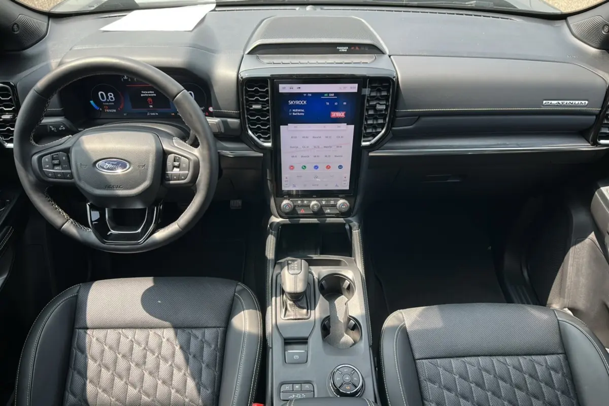Vue intérieure avant du Ford Ranger Platinum 2026, tableau de bord noir avec écran tactile vertical et volant cuir multifonctions.