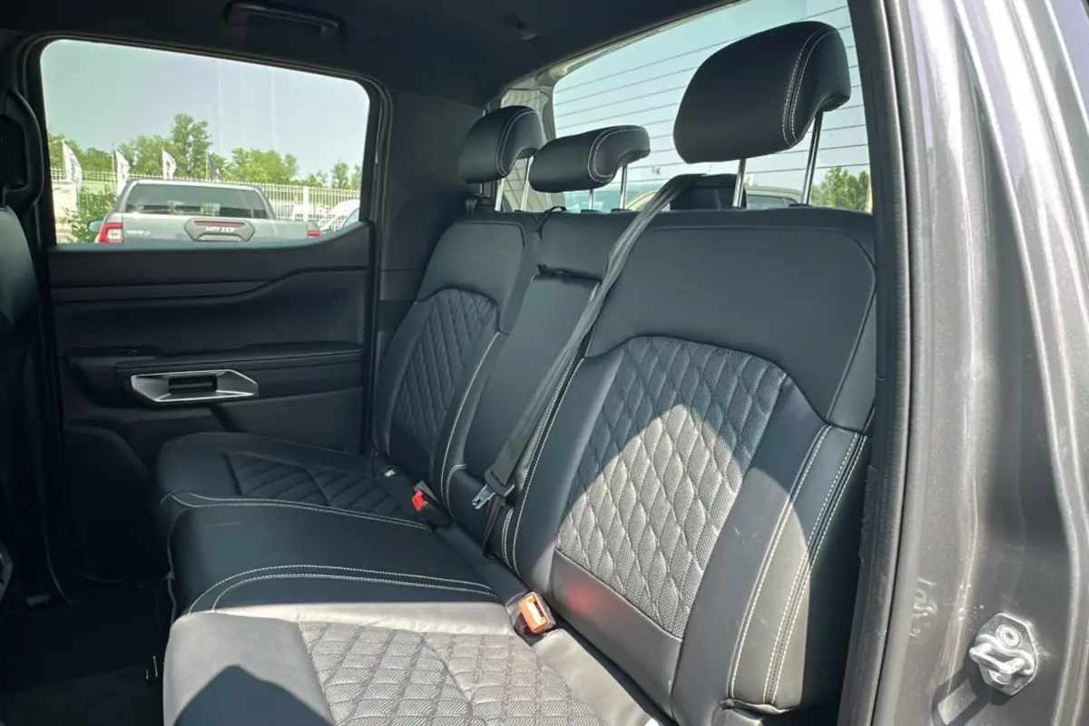 Vue intérieure côté droit des sièges arrière en cuir noir matelassé du Ford Ranger gris carbone 2026 avec rideau coulissant.