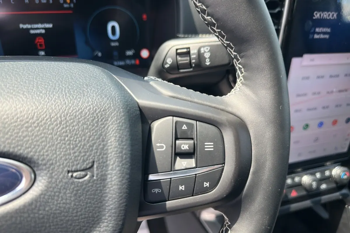 Gros plan sur le volant cuir multifonctions du Ford Ranger 2026, avec commandes intégrées et écran tactile en arrière-plan.