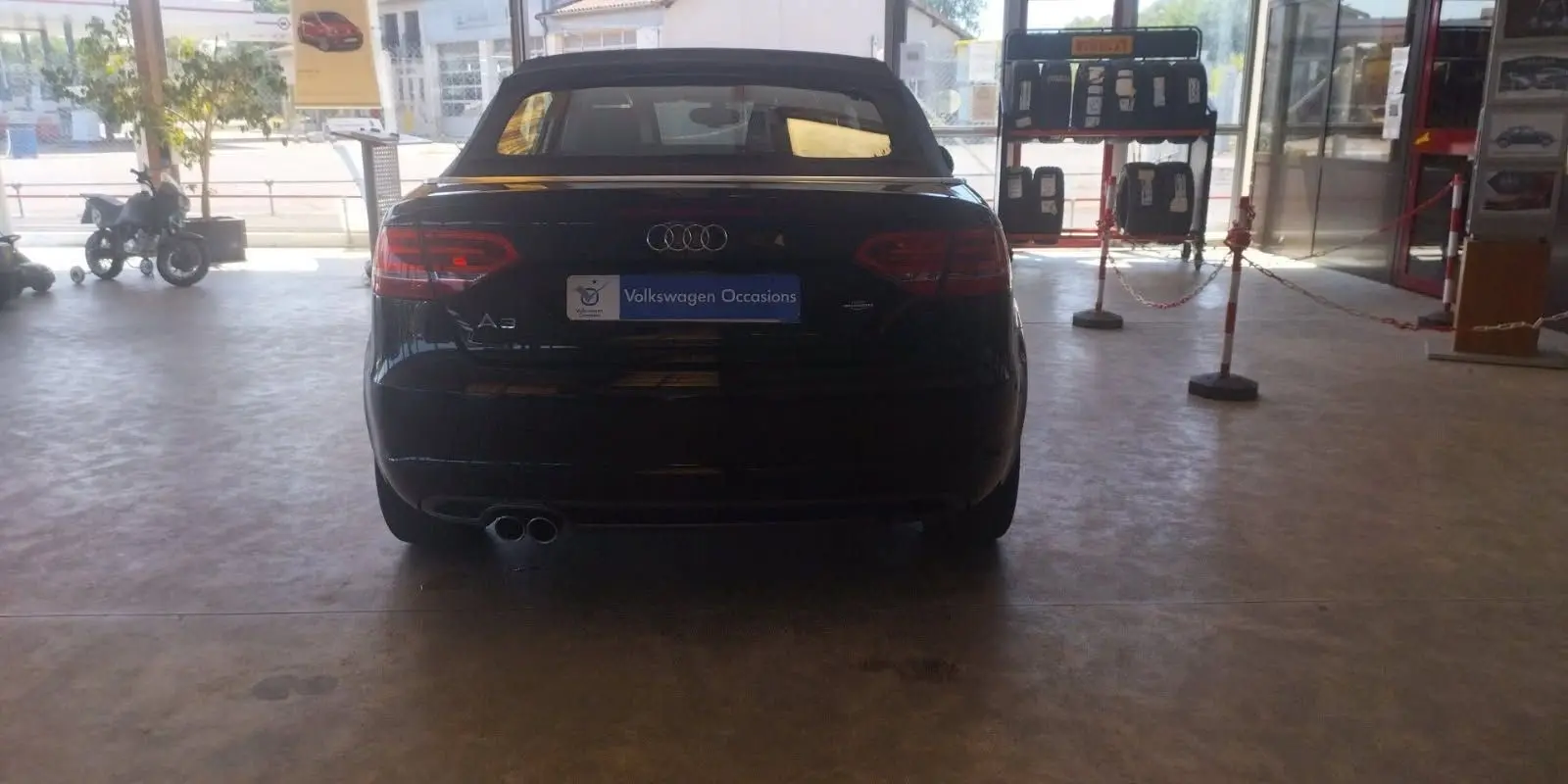 Vue arrière d'une Audi A3 Cabriolet noire de 2010 avec capote fermée, en intérieur de showroom.