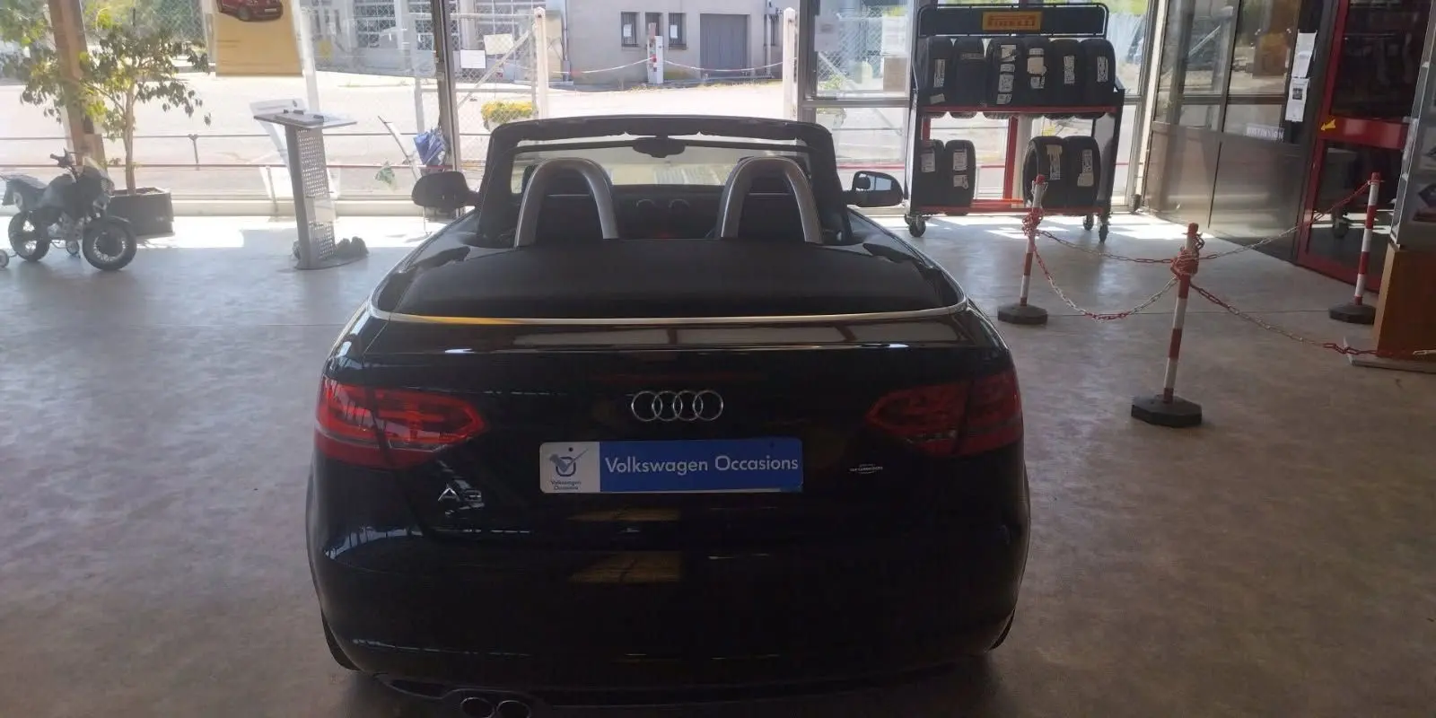 Vue arrière d'une Audi A3 Cabriolet noire 2010 avec capote ouverte, exposée en intérieur dans un showroom.