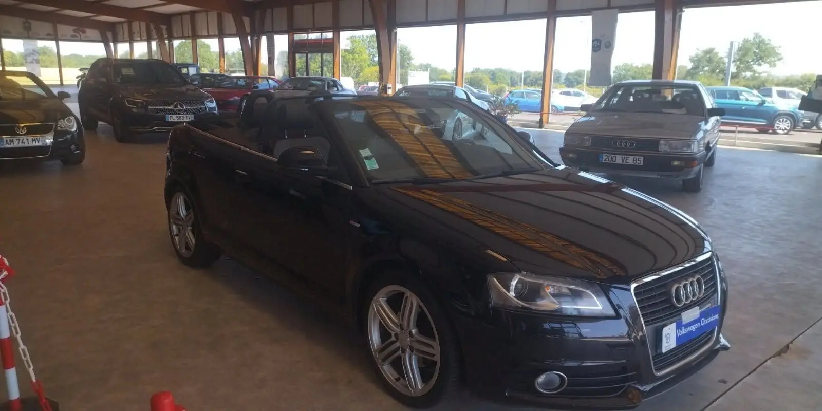 Audi A3 Cabriolet noir 2010 vue 3/4 avant droit, capote ouverte, jantes alliage et intérieur noir visible.