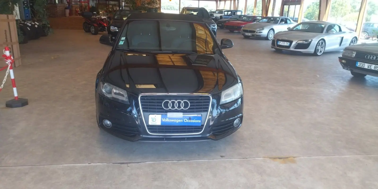 Audi A3 Cabriolet noir vue de face dans un showroom, mettant en valeur sa calandre et ses phares distinctifs.