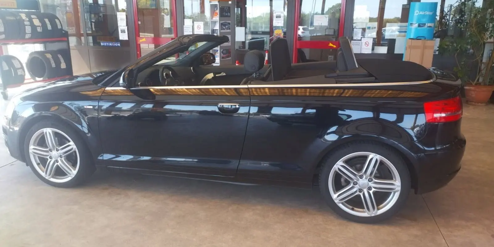 Audi A3 Cabriolet noir vue de profil côté gauche, capote ouverte et jantes alliage cinq branches visibles.