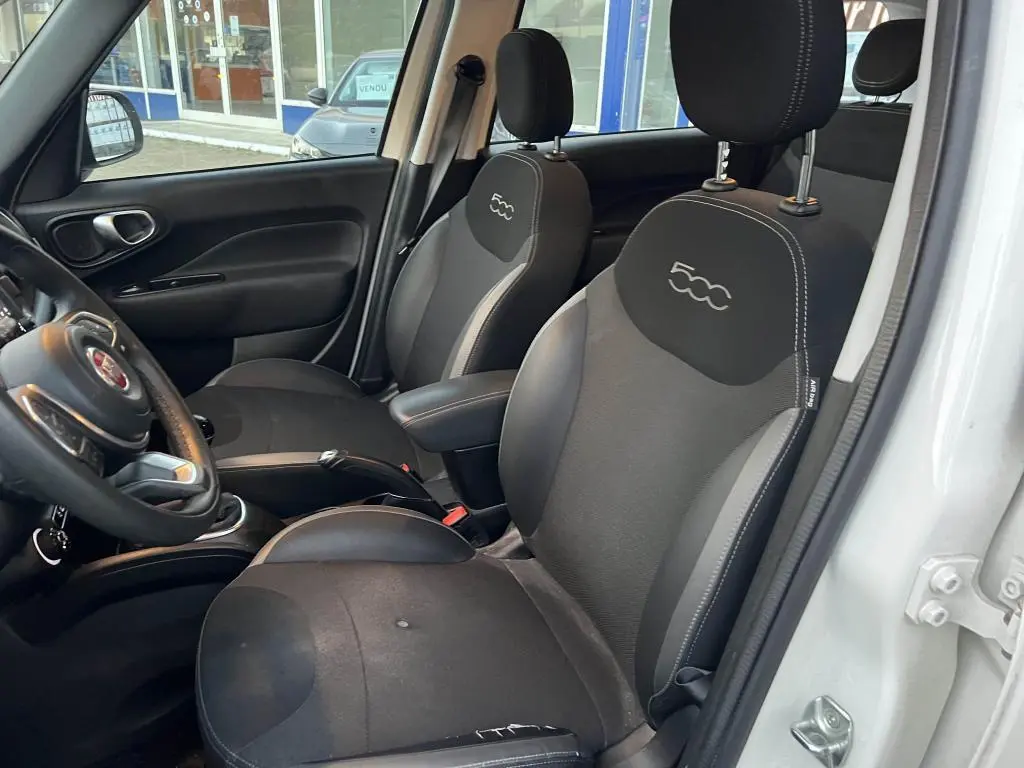 Vue intérieure côté conducteur de la Fiat 500L 2017, sièges noirs avec logo 500 brodé sur les appuie-têtes.