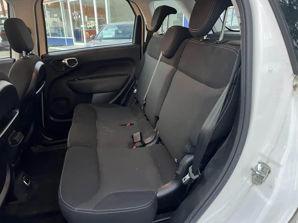 Vue intérieure côté droit montrant la banquette arrière noire de la Fiat 500L 2017 avec ceinture de sécurité et porte ouverte.