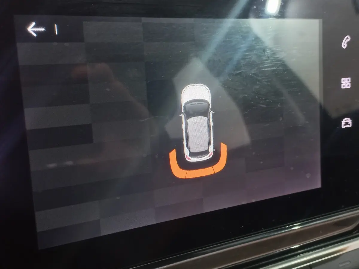 Affichage tactile montrant la vue aérienne d'une Citroën C3 noire avec alerte de proximité arrière en orange.