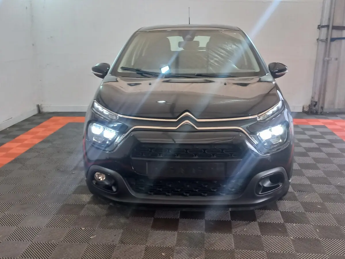 Vue frontale d'une Citroën C3 noire 2024 avec phares LED allumés dans un garage intérieur.