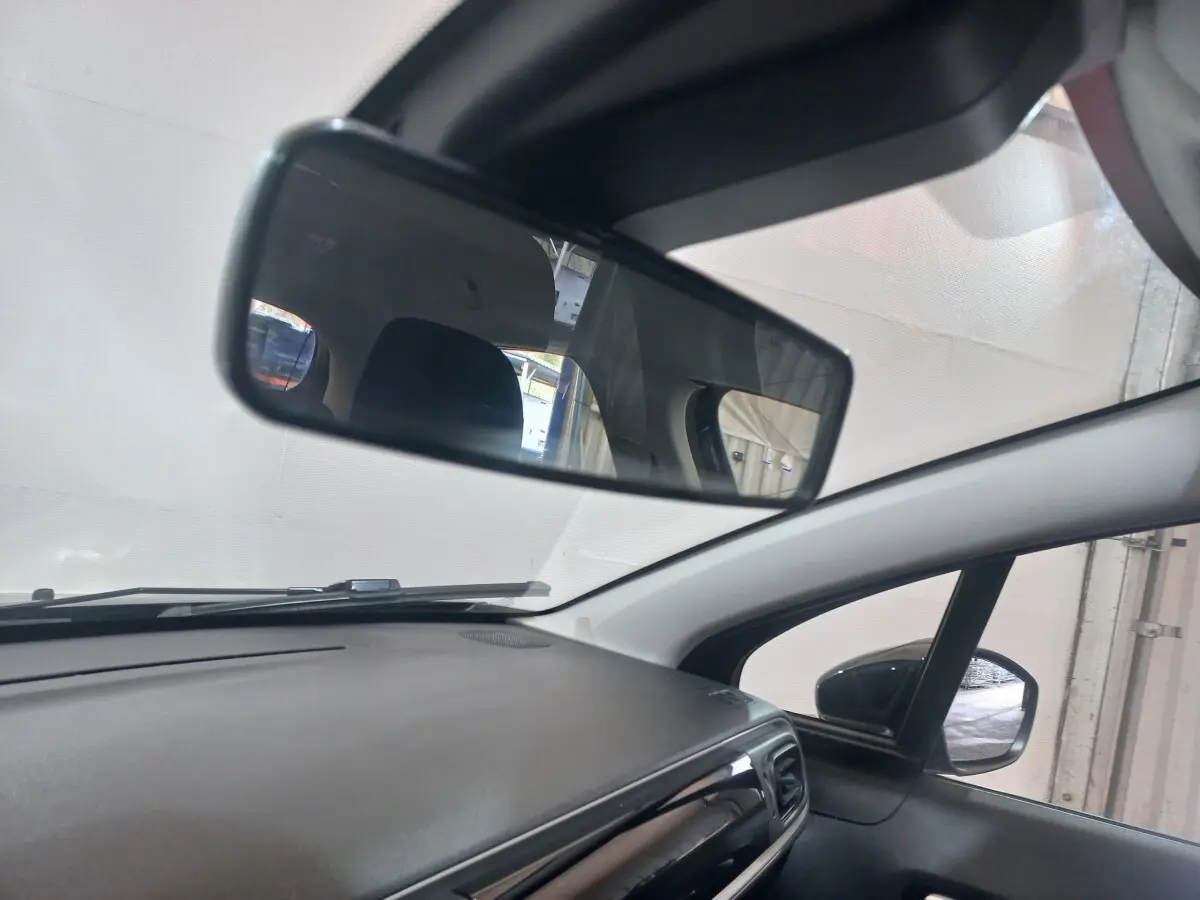 Vue intérieure du tableau de bord et rétroviseur central d'une Citroën C3 noire, avec rétroviseur extérieur droit visible.