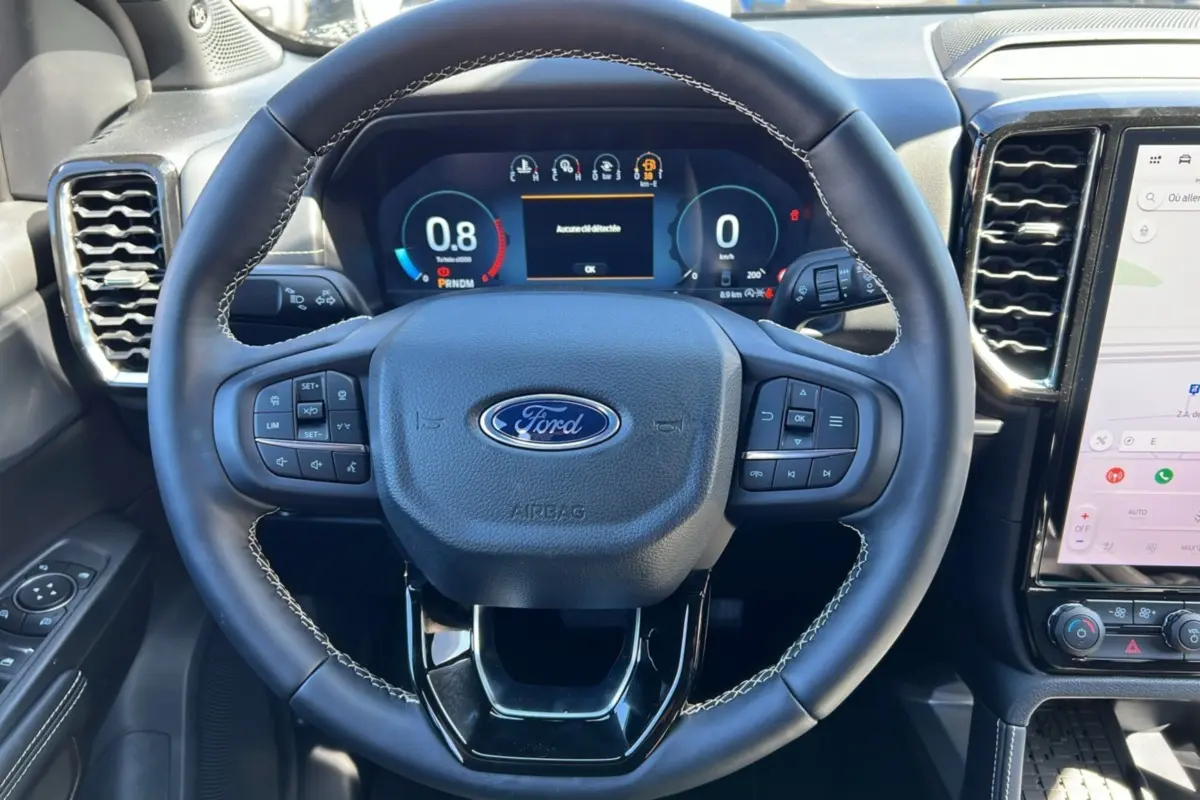 Vue intérieure centrée sur le volant cuir multifonctions du Ford Ranger noir agate avec tableau de bord numérique.