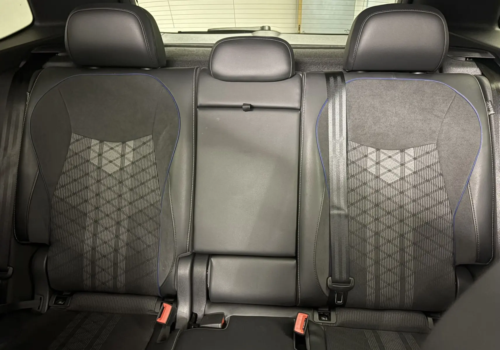 Vue intérieure des sièges arrière en tissu et cuir noir avec surpiqûres bleues du Volkswagen Tiguan 2025 R-Line Edition.