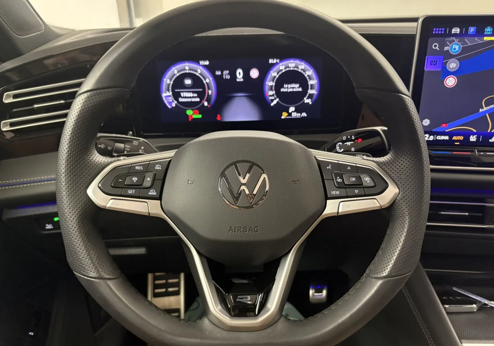Vue rapprochée du volant en cuir noir perforé du Volkswagen Tiguan 2025 avec tableau de bord numérique et écran tactile.