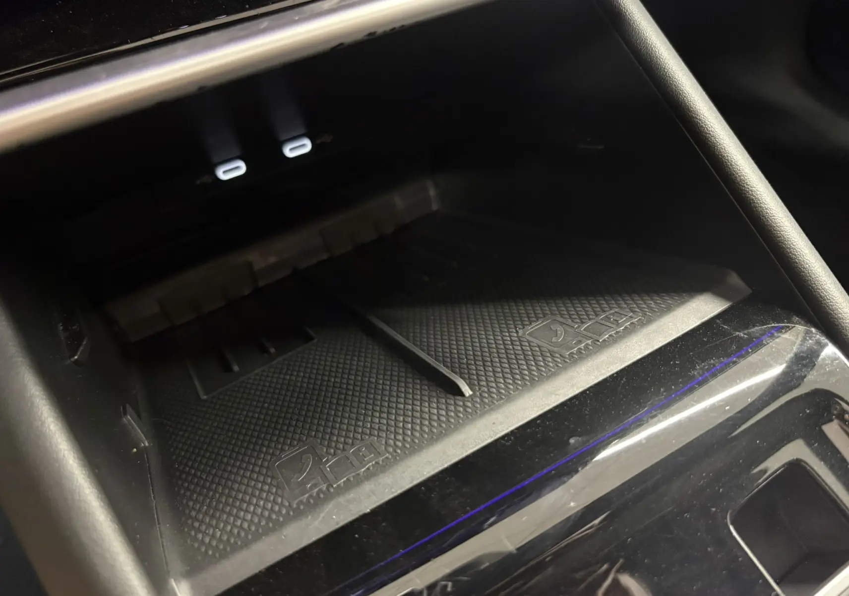 Détail de la console centrale du Volkswagen Tiguan 2025, zone de recharge sans fil avec deux ports USB-C éclairés.