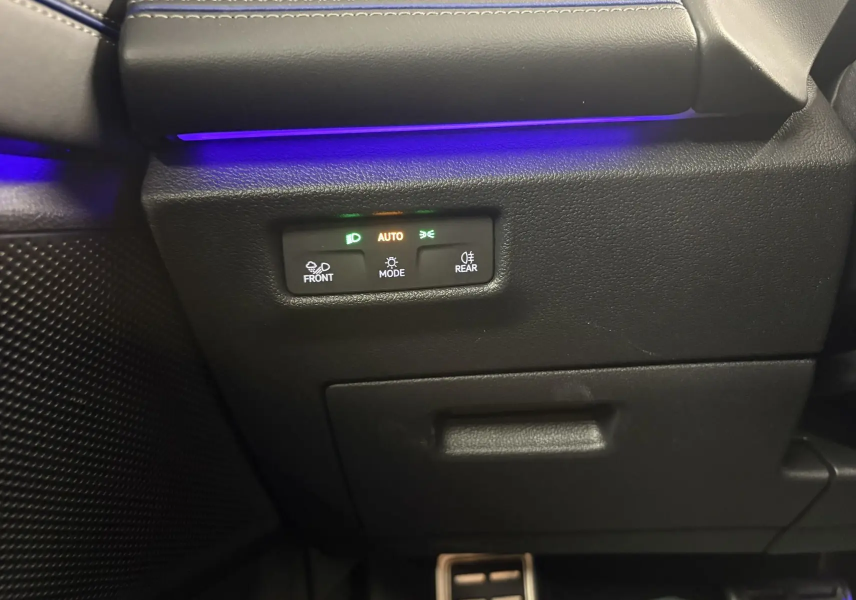 Détail du panneau de commandes d’éclairage avec éclairage d’ambiance bleu dans l’habitacle du Volkswagen Tiguan noir intense nacré.