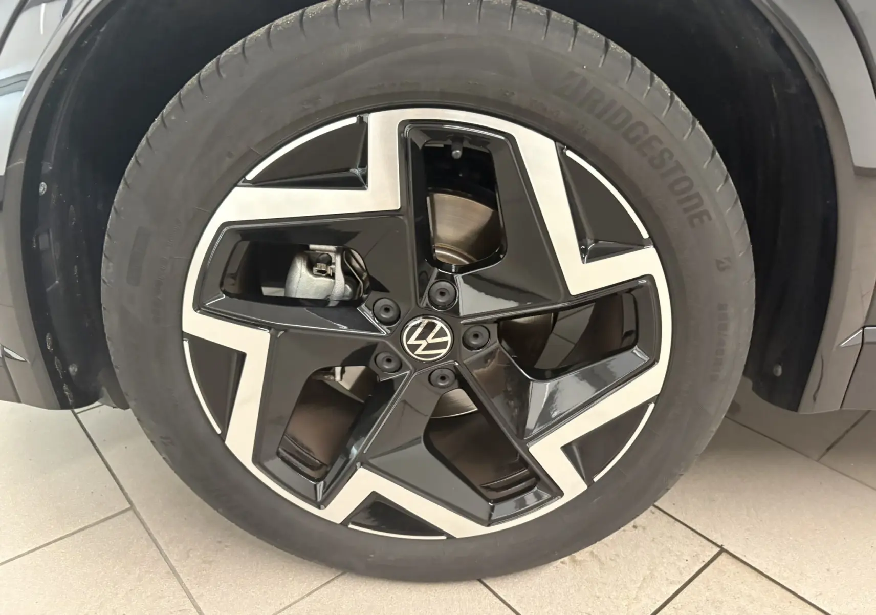 Gros plan sur la jante noire et argentée du Volkswagen Tiguan 2025, version R-Line avec peinture Noir Intense Nacré.