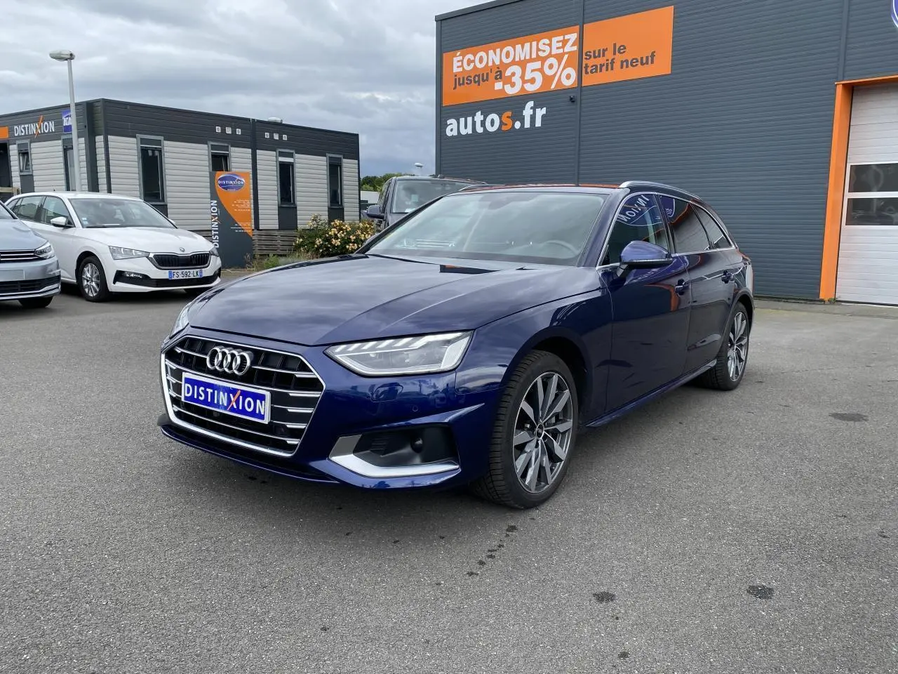 Audi A4 Avant bleu Navarre vue 3/4 avant droit avec jantes 5 branches et calandre chromée sur parking extérieur