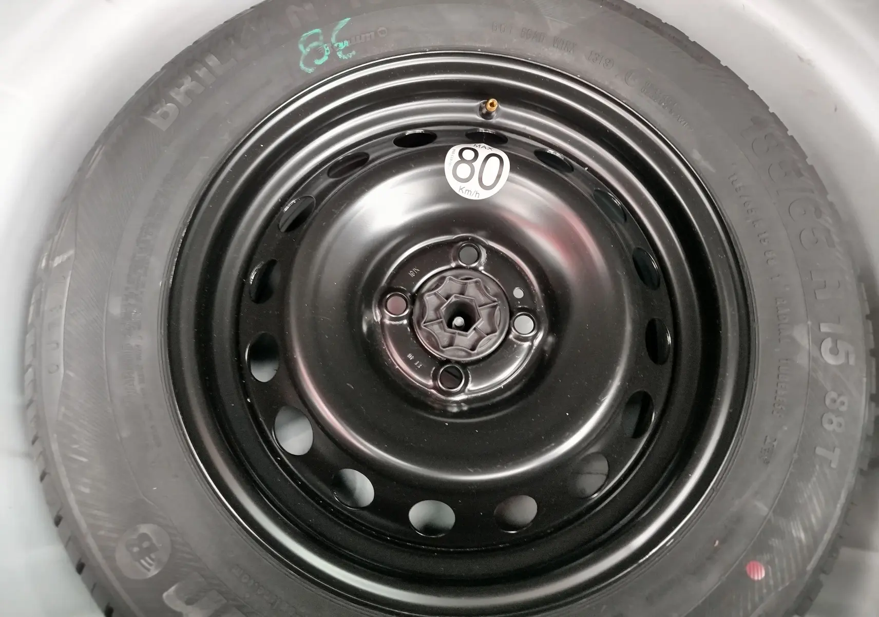 Gros plan sur la roue de secours noire avec étiquette 80 km/h du Dacia Sandero blanc glacier 2019