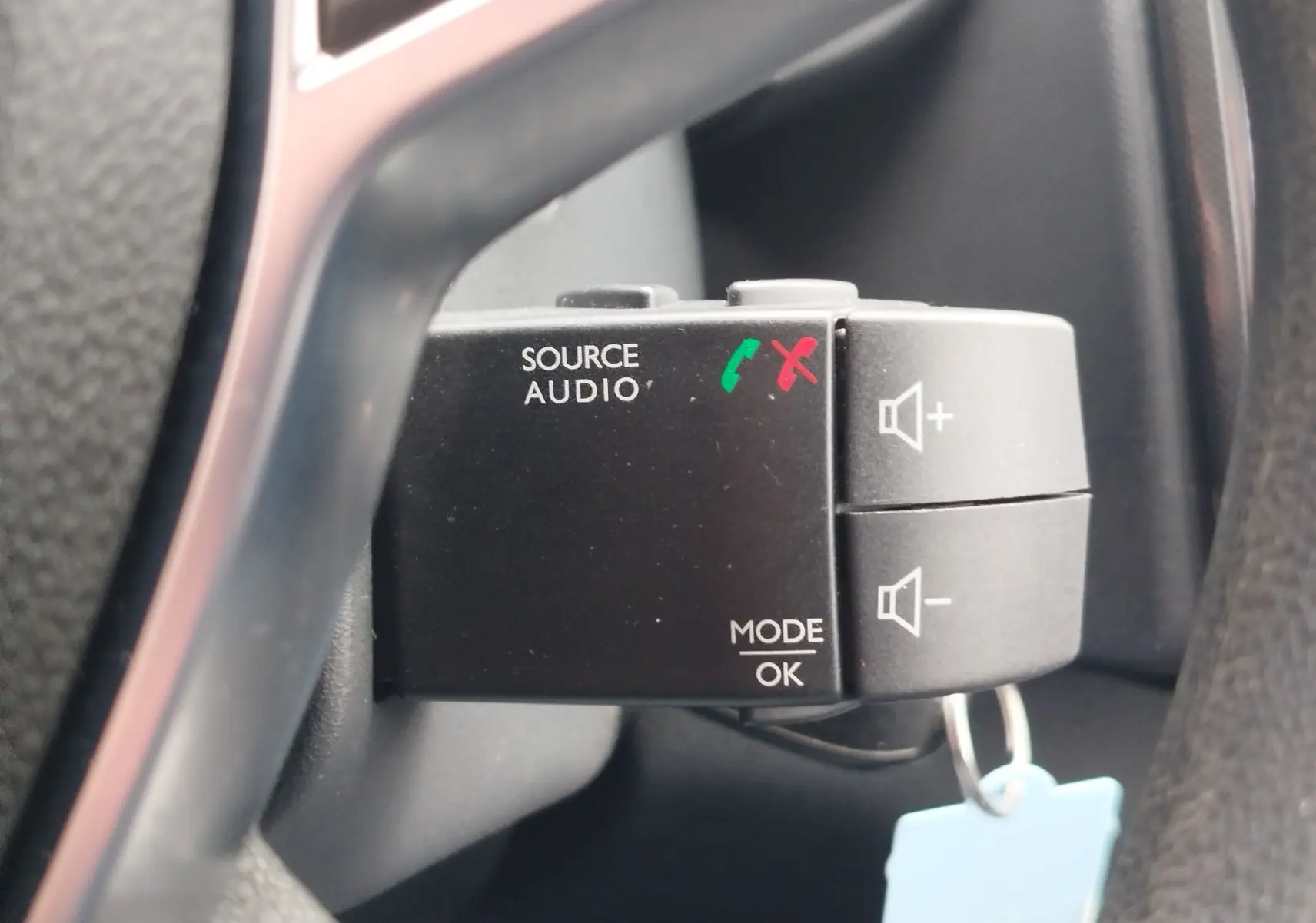 Gros plan sur la commande audio au volant de la Dacia Sandero blanc glacier, avec boutons de volume et gestion d'appels.