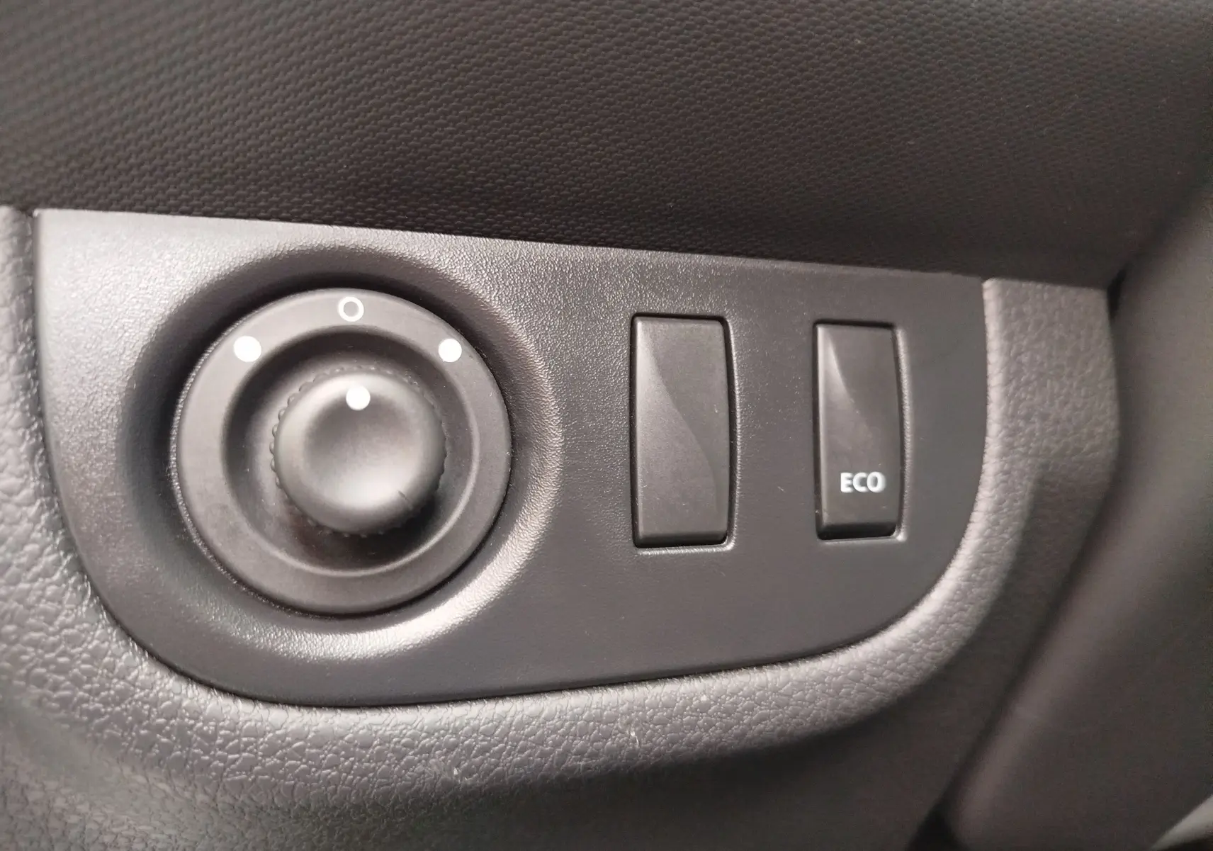 Gros plan sur les commandes de réglage des rétroviseurs et bouton ECO à l'intérieur d'une Dacia Sandero blanc glacier 2019