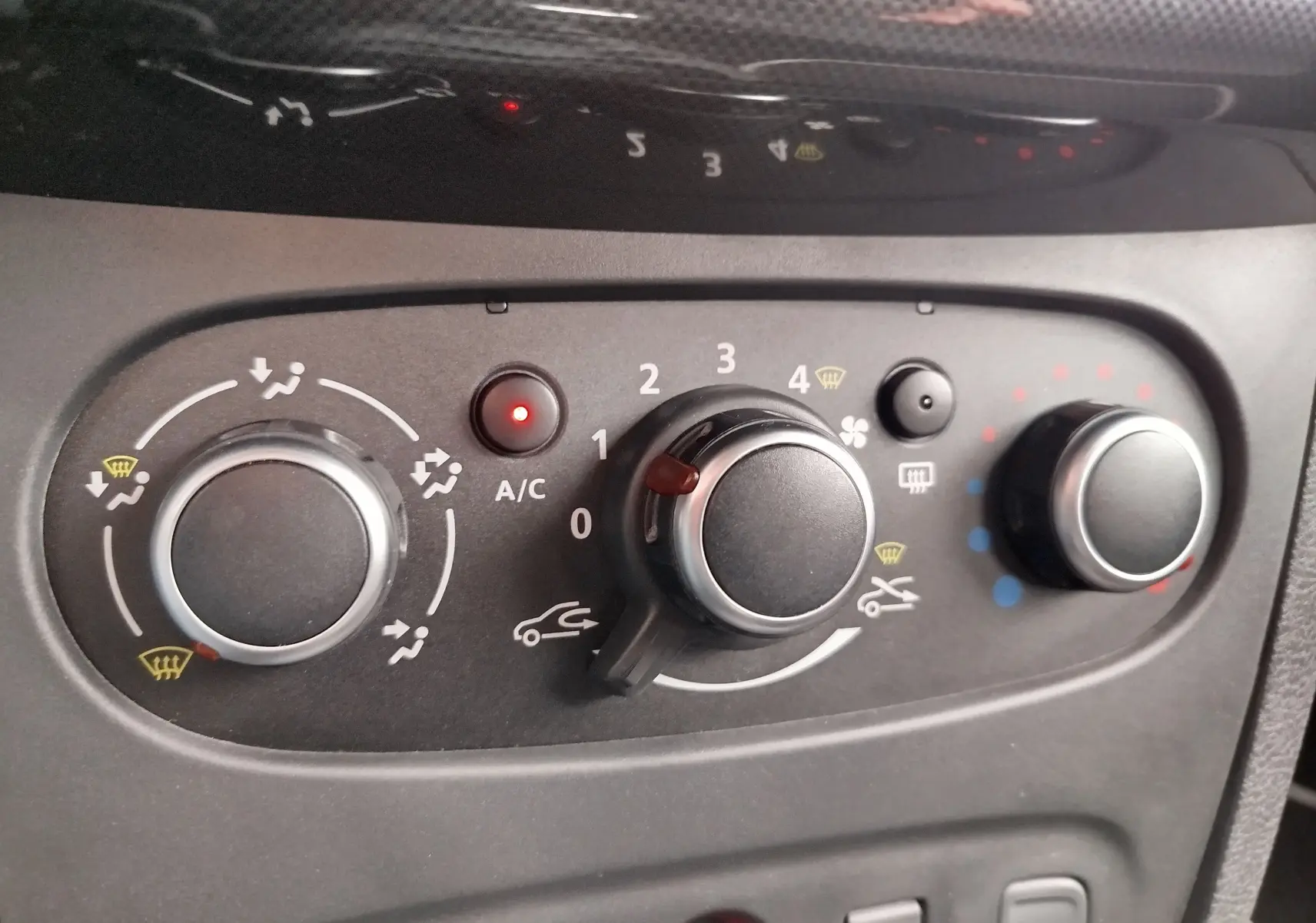 Gros plan sur les commandes de climatisation du tableau de bord de la Dacia Sandero blanc glacier 2019, version Lauréate.