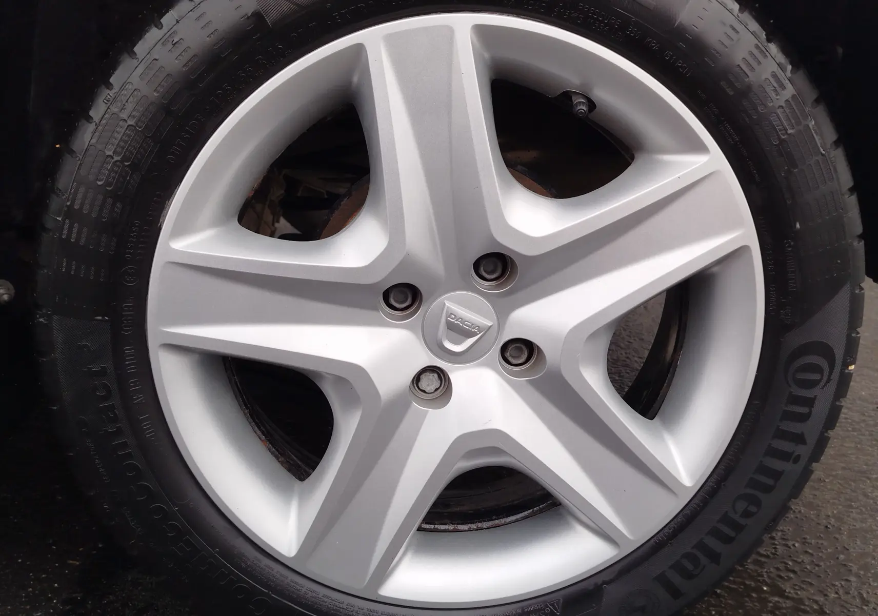 Gros plan sur la roue avant droite d'une Dacia Sandero blanc glacier de 2019 avec pneu Continental.