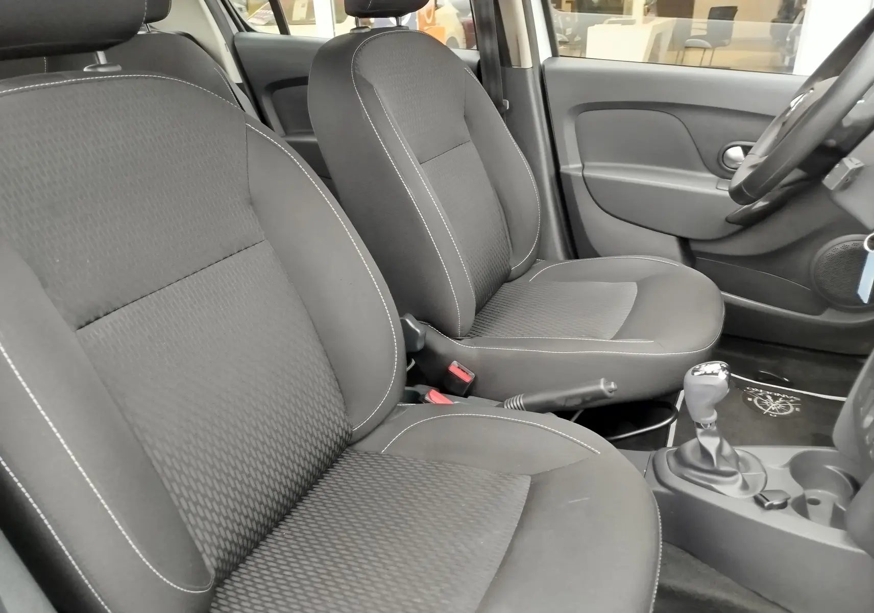 Intérieur du Dacia Sandero 2019 en tissu gris, vue côté droit sur les sièges avant et levier de vitesse.