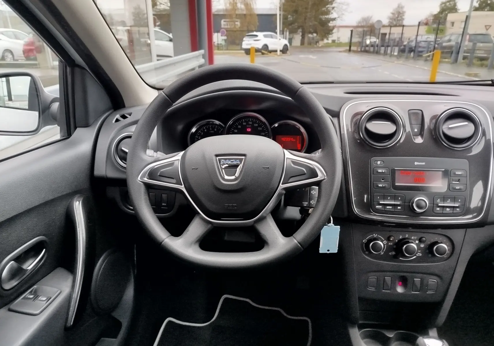Intérieur de la Dacia Sandero 2019 vue depuis le siège conducteur, tableau de bord noir avec volant et console centrale.