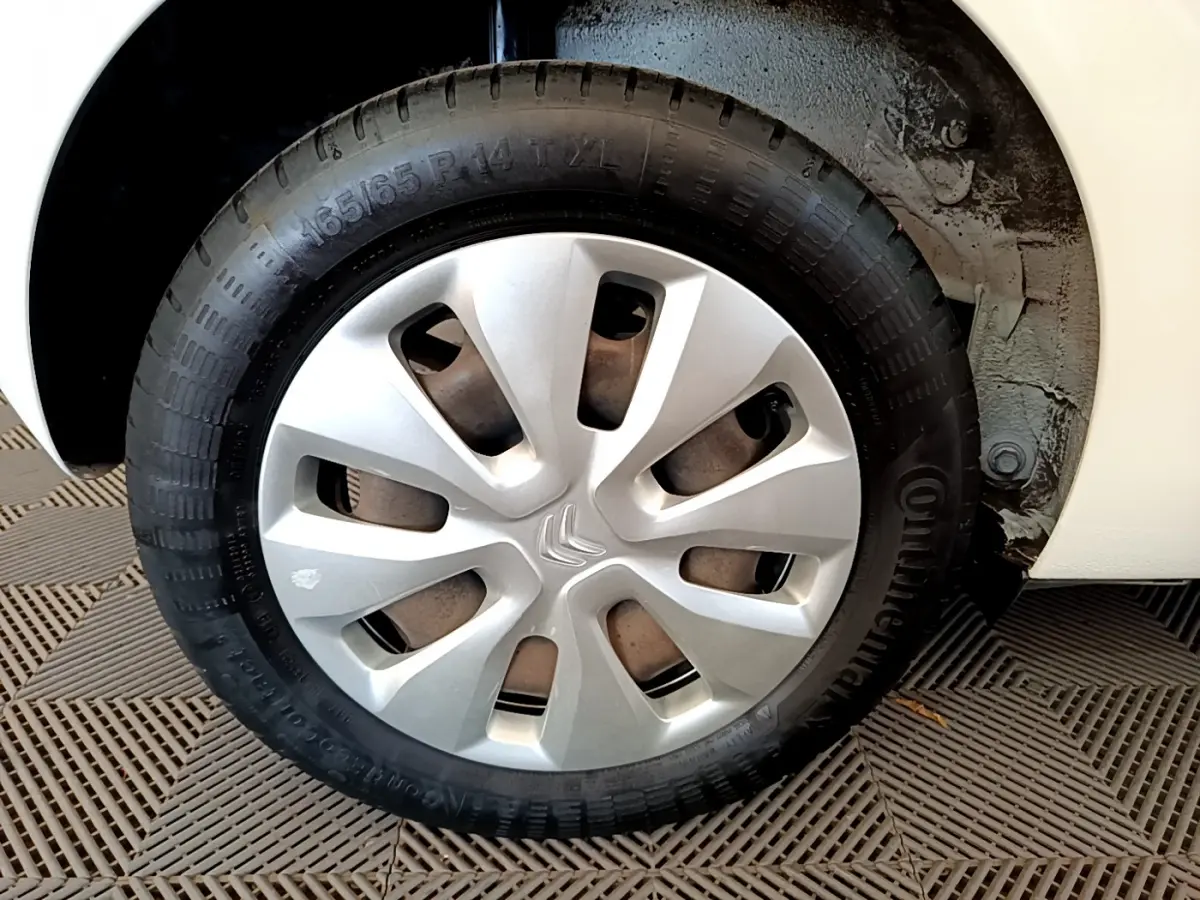 Gros plan sur la roue avant droite d'une Citroën C1 blanche avec enjoliveur argenté et pneu Continental.