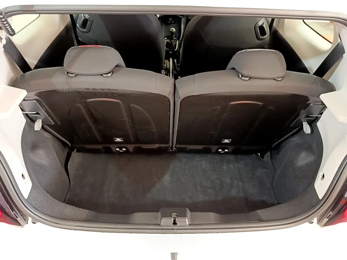 Vue du coffre arrière ouvert de la Citroën C1 blanche, montrant la banquette arrière 2 places rabattue 50/50.