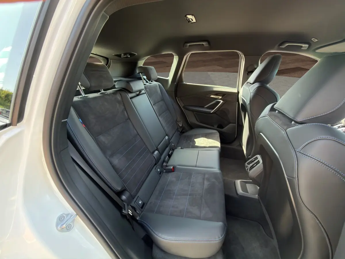 Vue intérieure côté droit montrant les sièges arrière en cuir et alcantara noirs du BMW X1 blanc 2025 M SPORT.