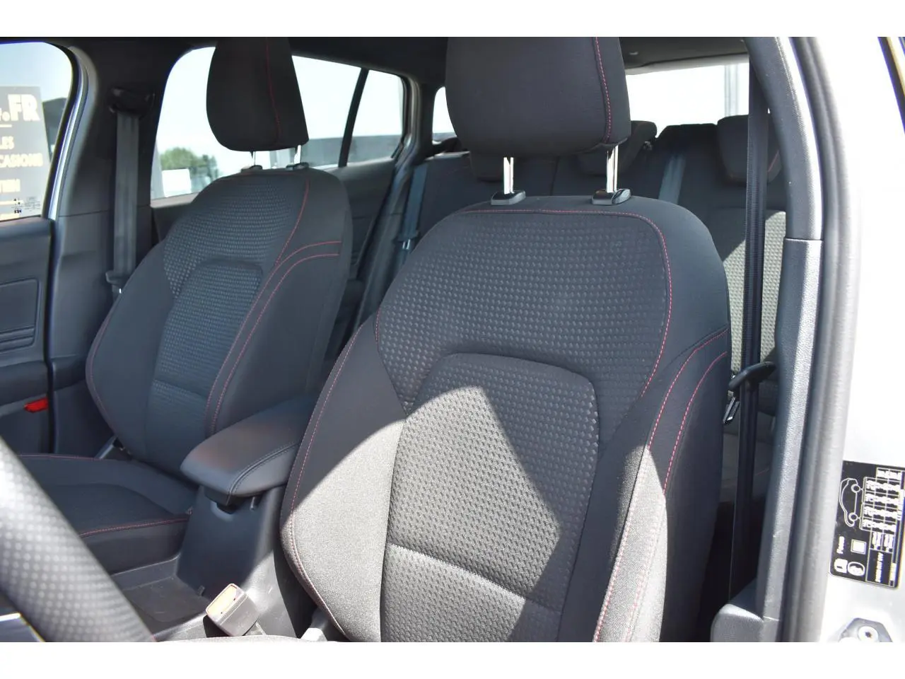 Vue intérieure côté avant droit montrant les sièges tissu noir avec surpiqûres rouges du Ford Focus SW 2025 Moondust Silver.