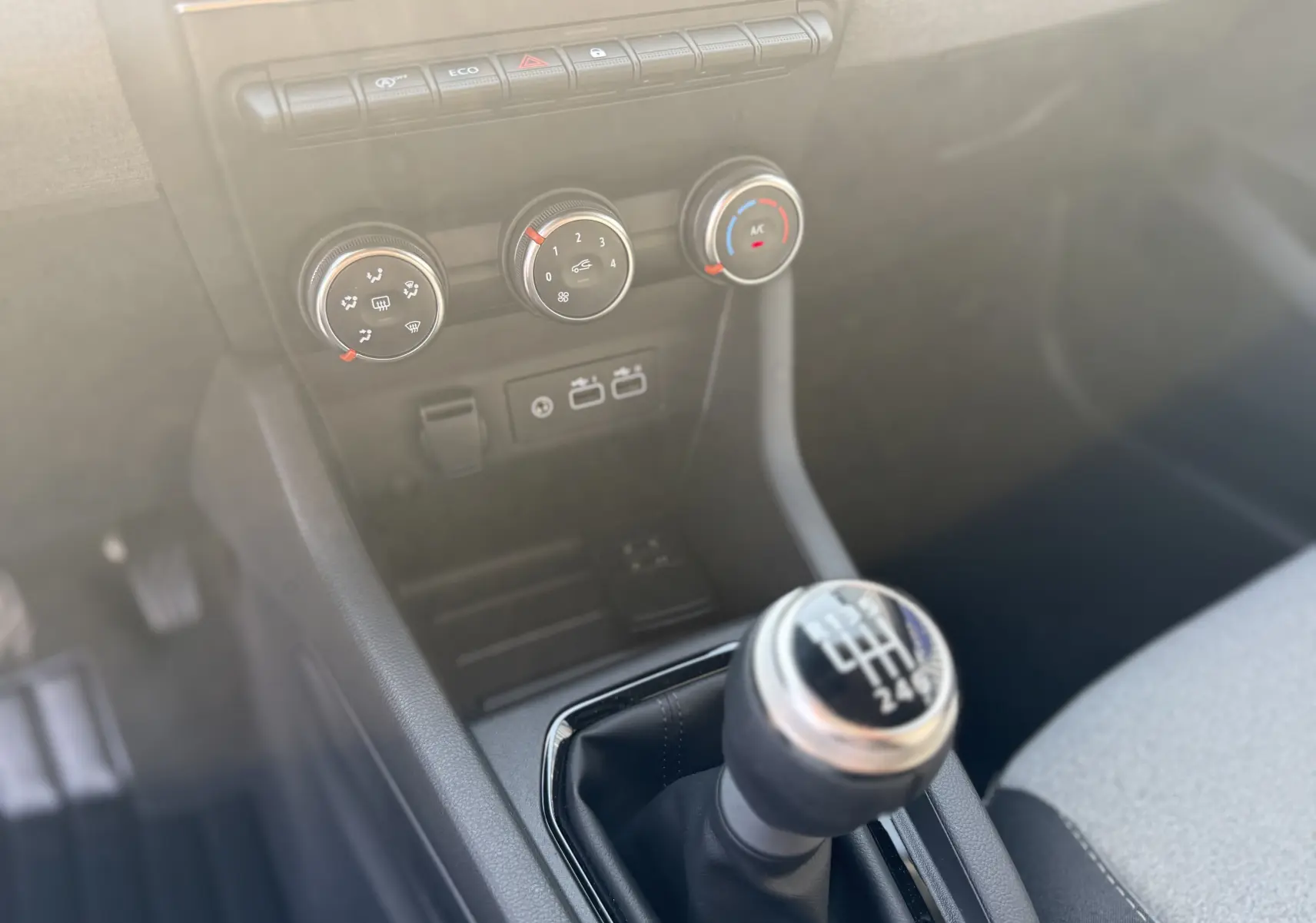 Gros plan sur la console centrale de la Renault Clio 1.5 dCi 2025, boîte manuelle et commandes de climatisation.