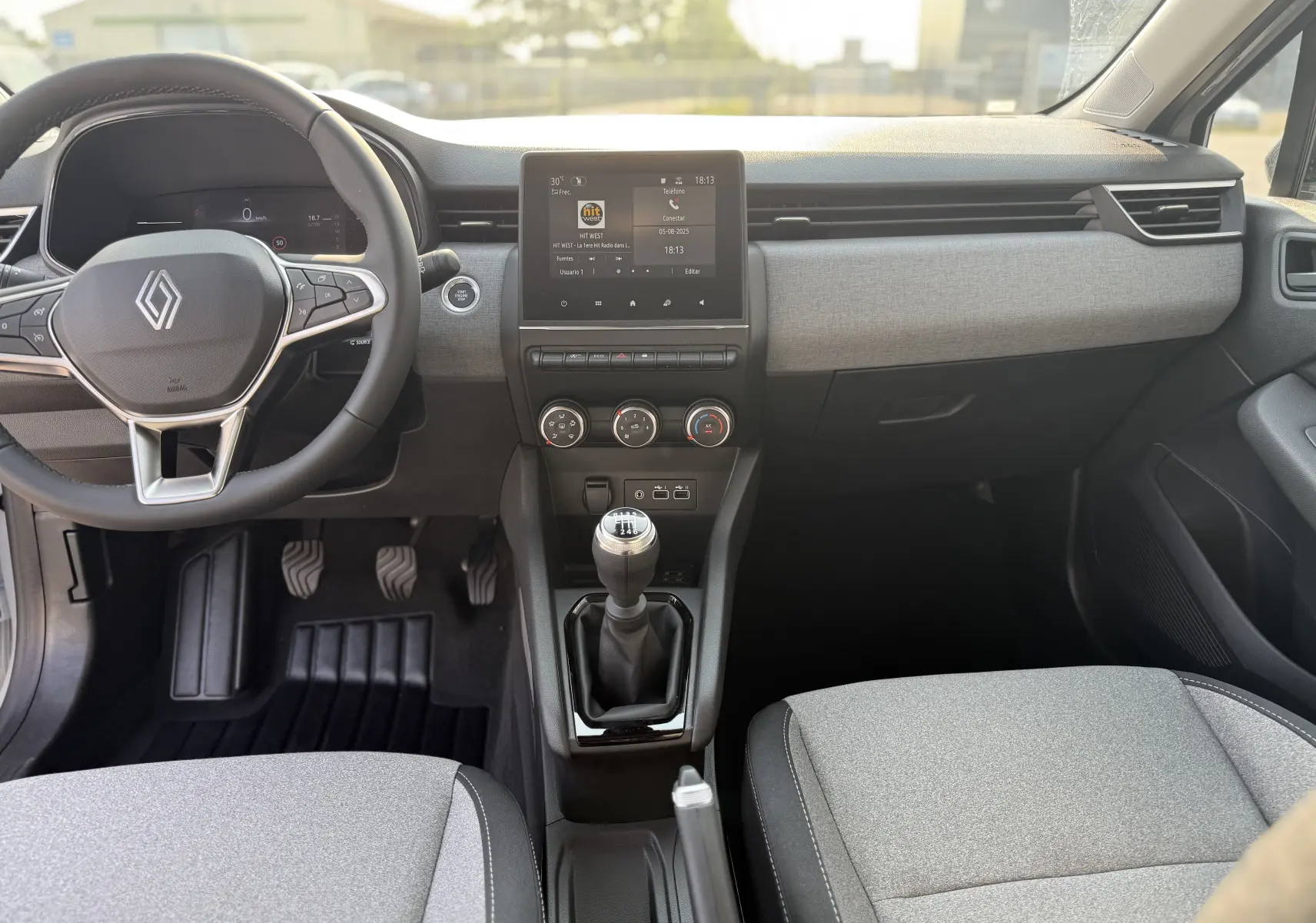 Intérieur avant de la Renault Clio gris rafale métal 2025, vue centrée sur le tableau de bord et la boîte manuelle.
