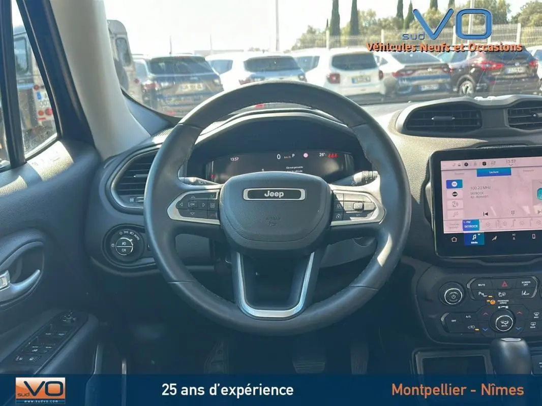 Vue centrée sur le volant Jeep noir du Renegade 2024 avec tableau de bord numérique et écran tactile multimédia.
