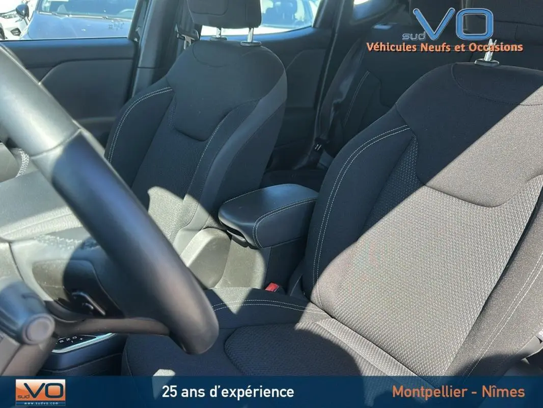 Intérieur du Jeep Renegade 2024 noir, vue sur sièges avant avec accoudoir central et volant partiellement visible.