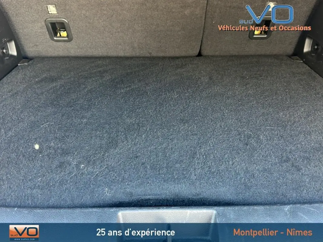 Coffre spacieux et tapissé en noir du Jeep Renegade 2024 e-Hybrid Summit, avec fixations visibles sur la paroi arrière.